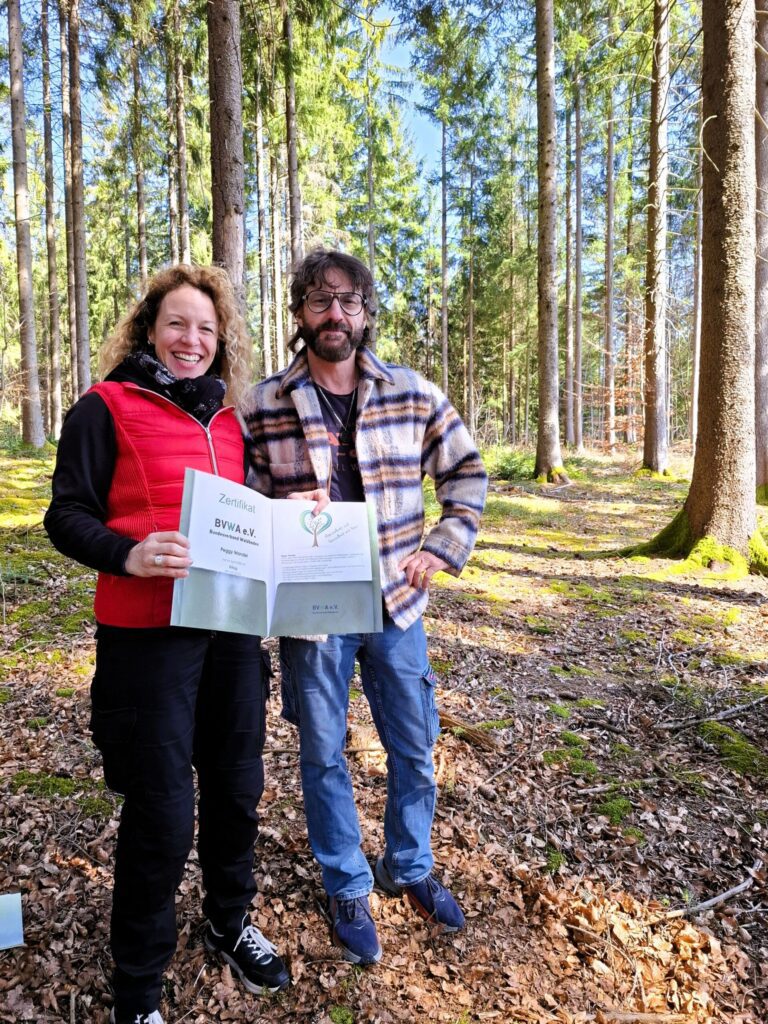 Jörg Meier verleiht Peggy Wandel das Zertifikat "Kursleiterin Waldbaden". Peggy Wandel ist Kursleiterin. Waldbaden: Mit Trainer Jörg Meier bei der Zertifikatsübergabe - natürlich im Wald.