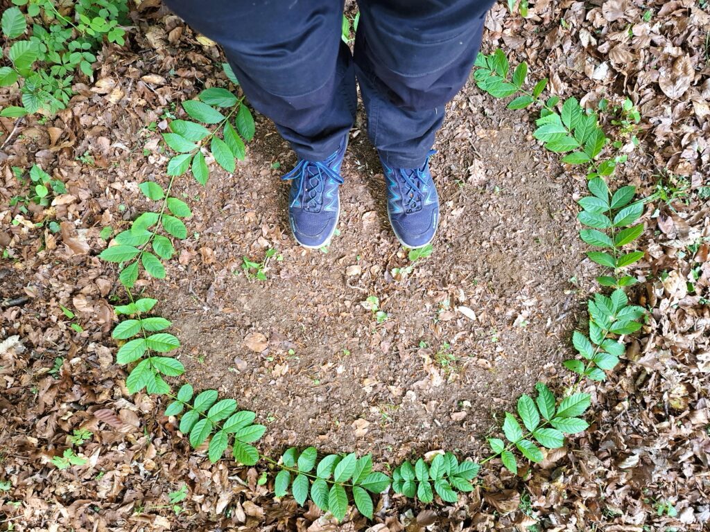 Füße in Kranz aus Eschenblättern auf Waldboden