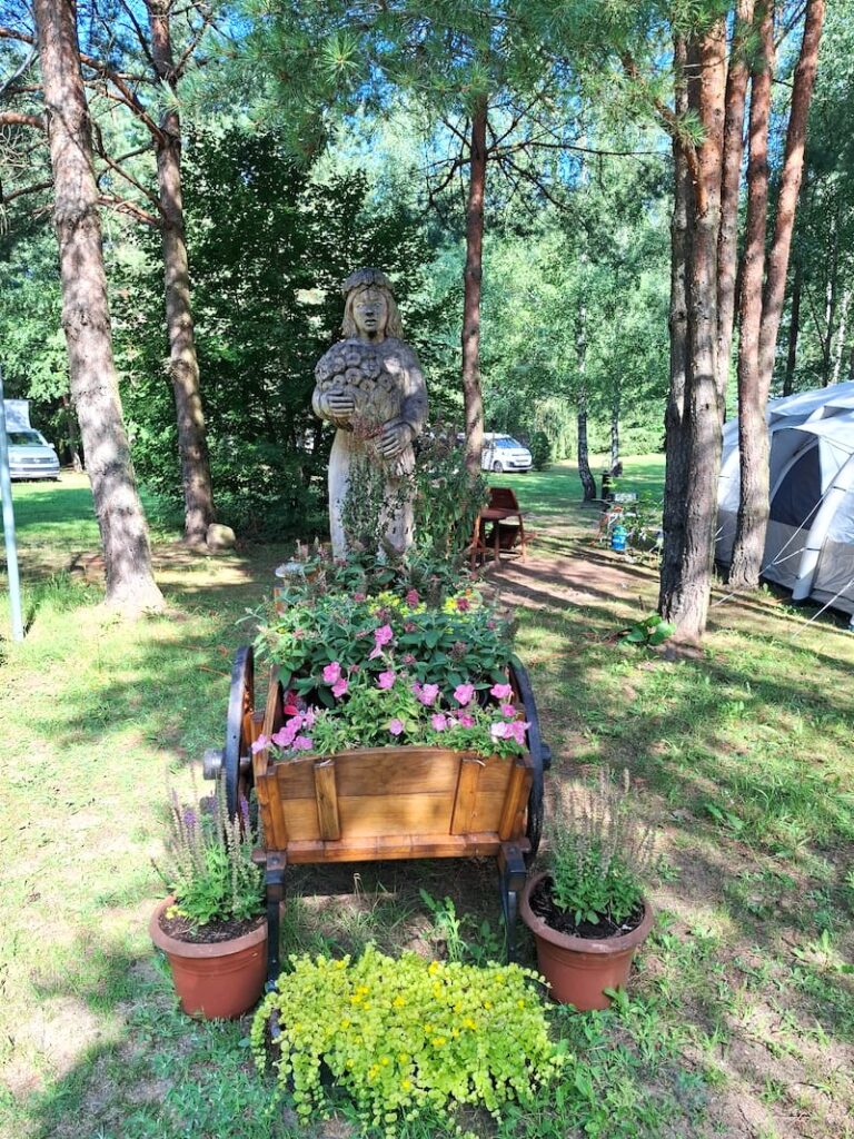 Holzfigur und Blumen auf Campingplatz Masurische Seenplatte