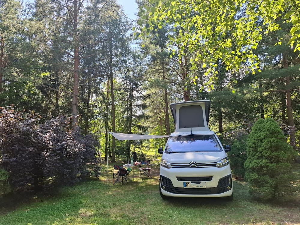 Vanster auf Campingplatz unter Bäumen an der Masurischen Seenplatte