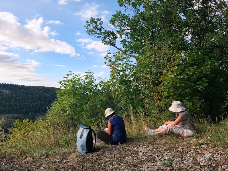 Zwei Frauen mit Hut schreiben auf Waldlichtung